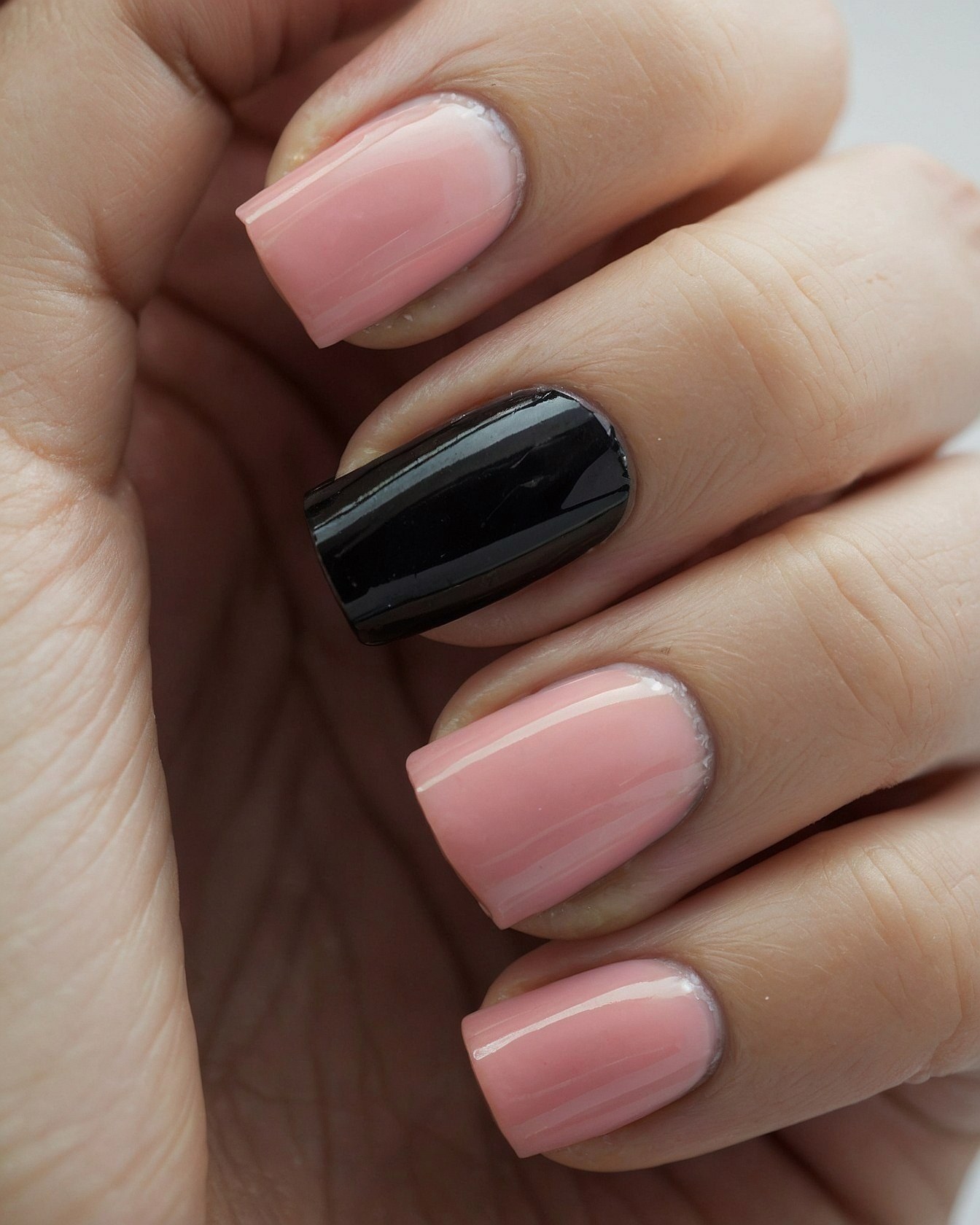 A single black nail pops against soft blush pink