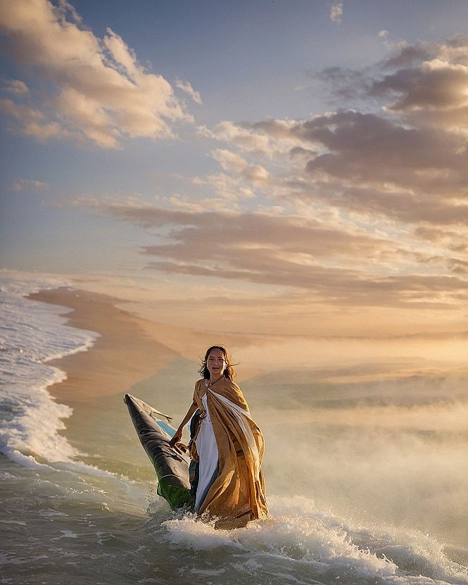 A Gold Draped Cloak Sweeping Over a White Gown Amid Sea Spray