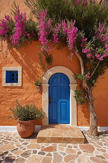 Sunlit terracotta walls framed by vibrant magenta bougainvillea and cobalt blue doors
