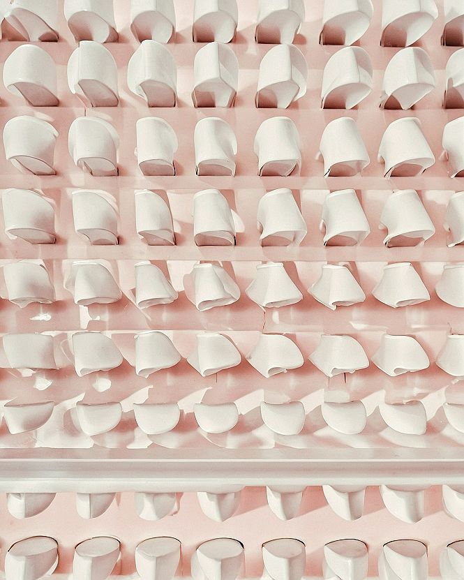 Rigid geometric white forms aligned across a #fce3de pink backdrop