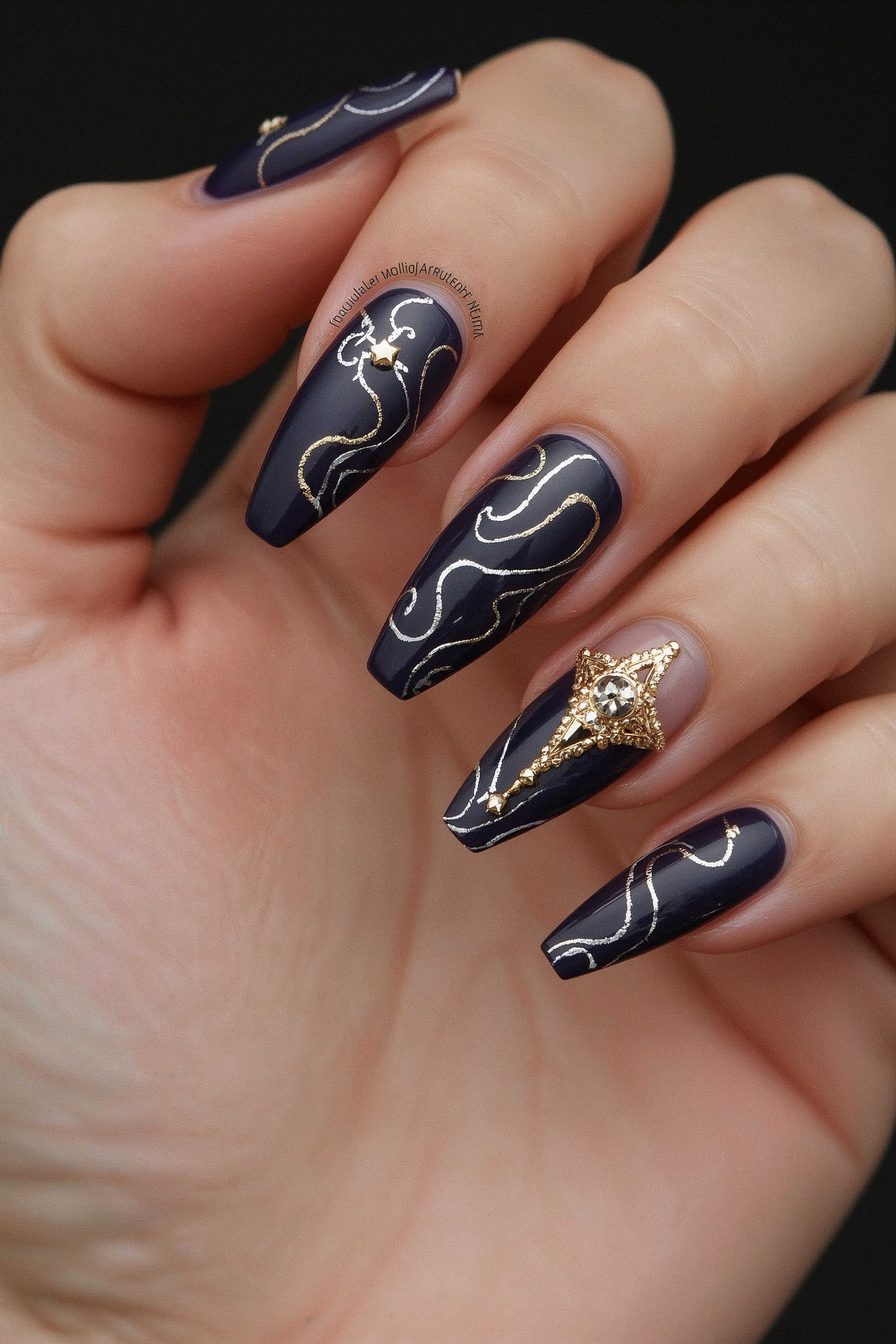 Close-up of navy almond nails with gold accents
