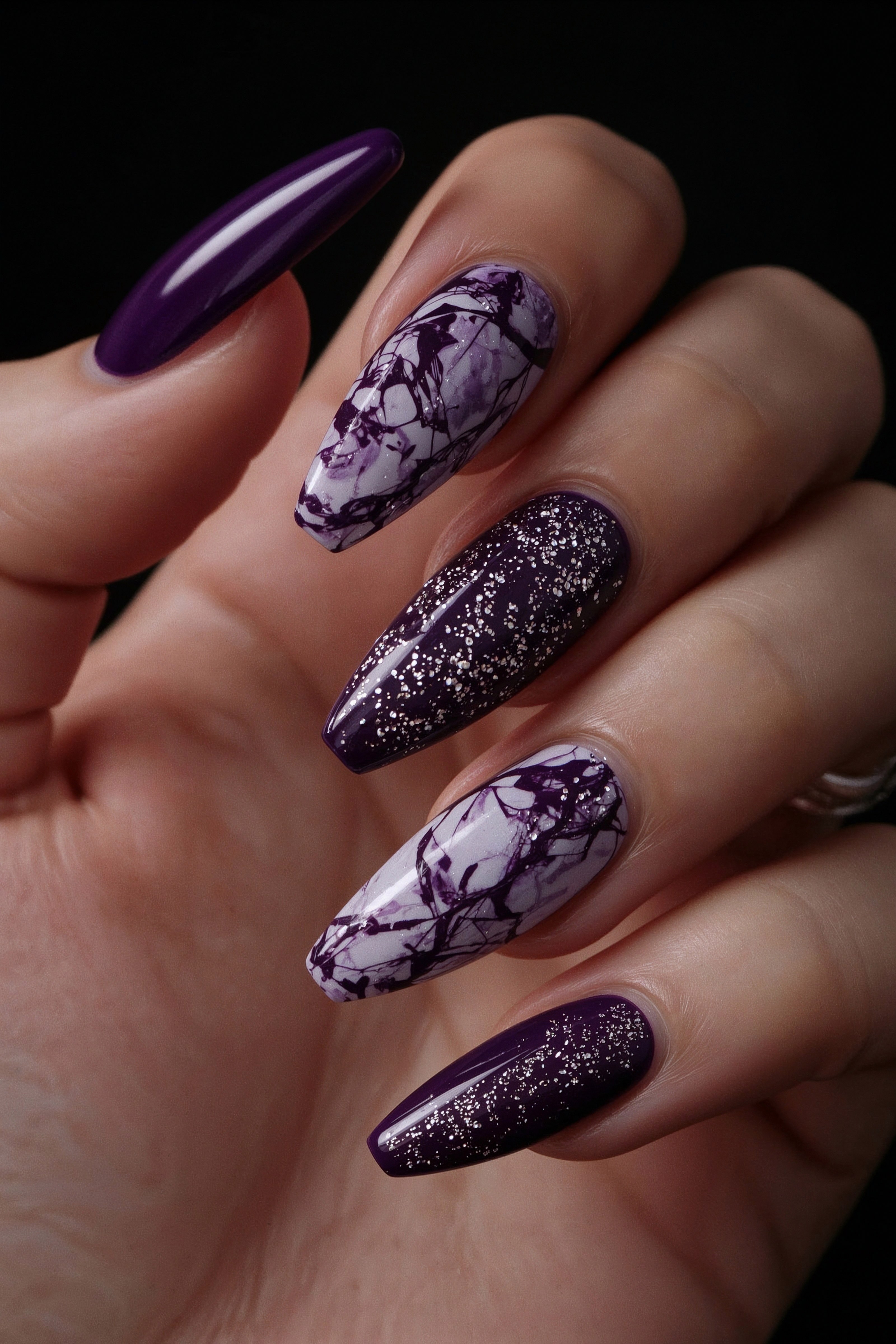Close-up of purple marble and glitter nails