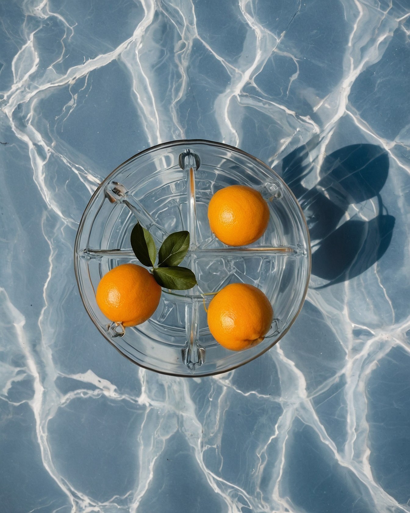 Oranges in a glass dish against rippling water