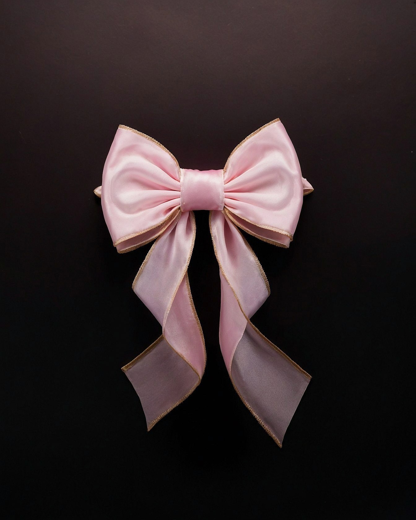 Soft pink bow with metallic gold trim overhead