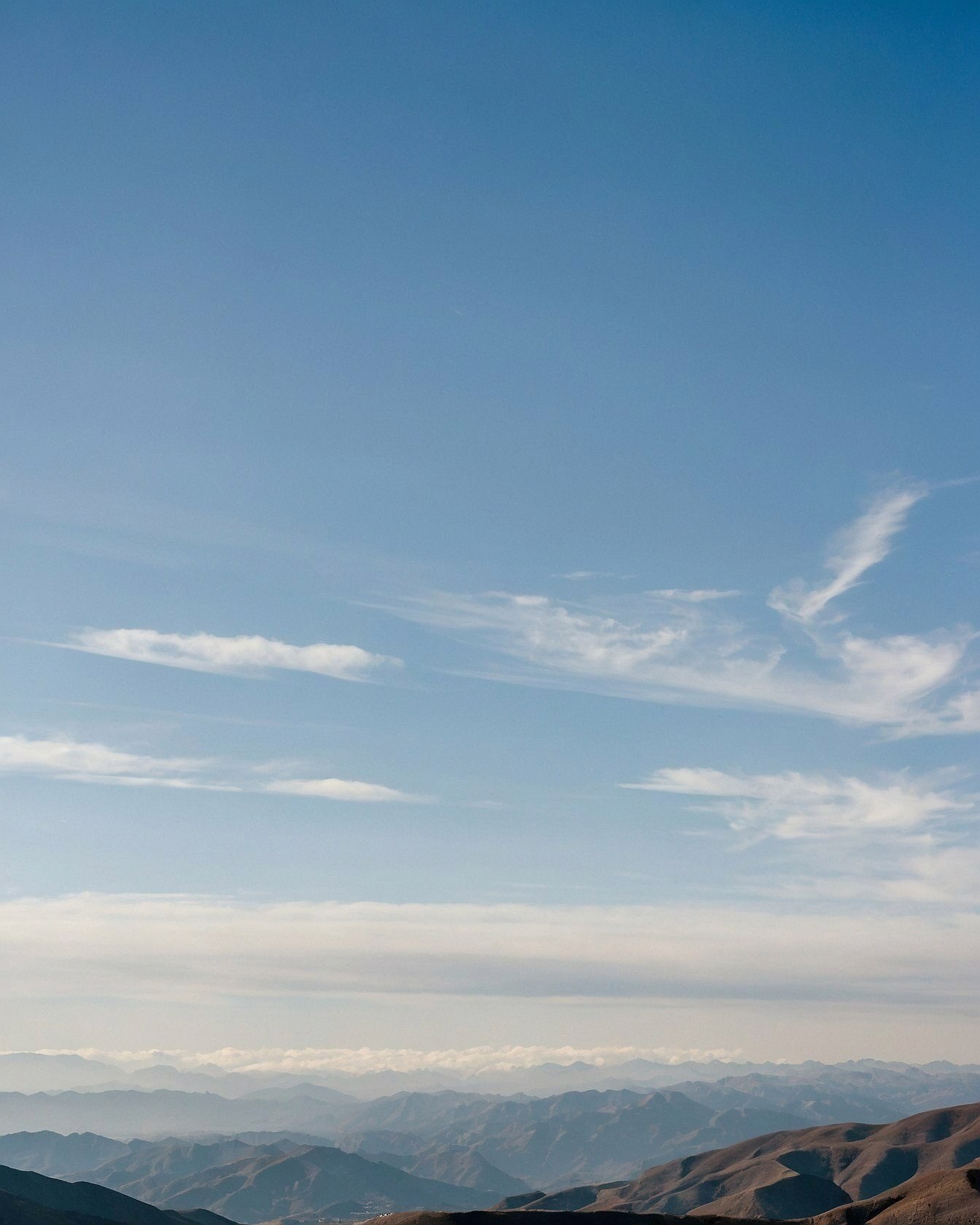 Wide shot of layered mountains under a vast blue sky