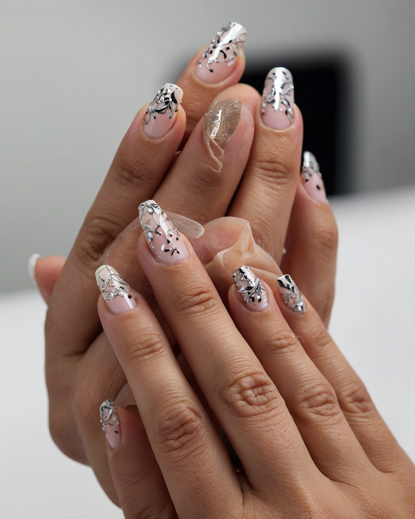 Close-up of sheer French tips with metallic accents
