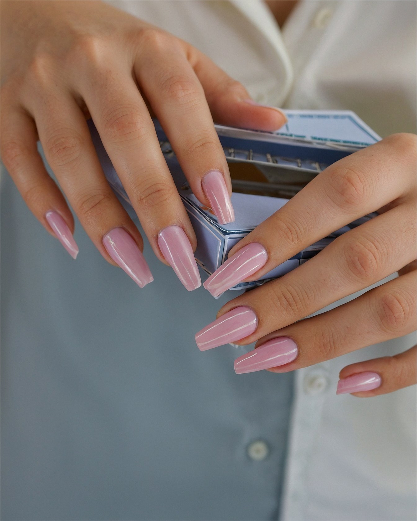 Close-up of soft pink coffin nails holding a box
