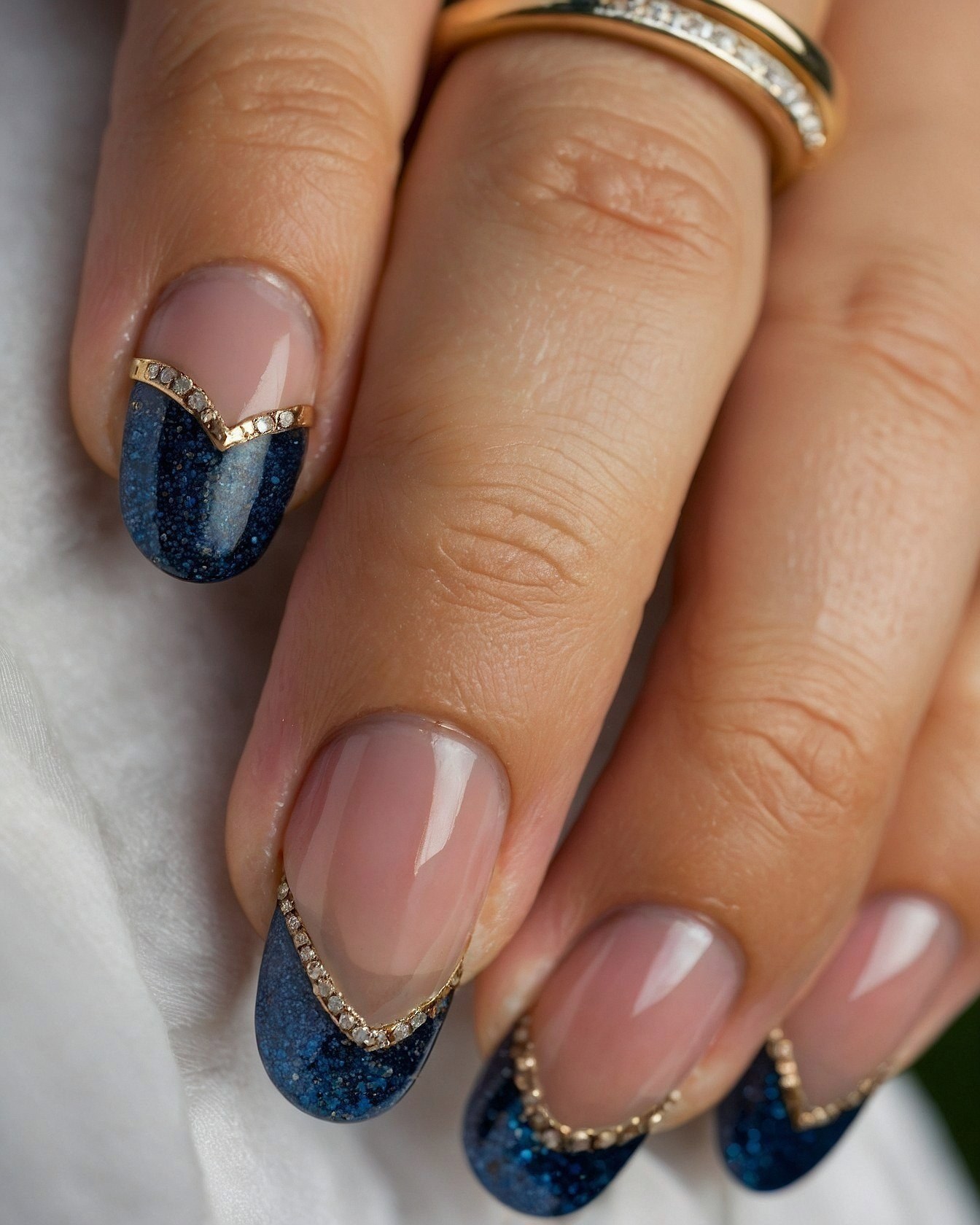 Close-up of navy almond nails with gold accents