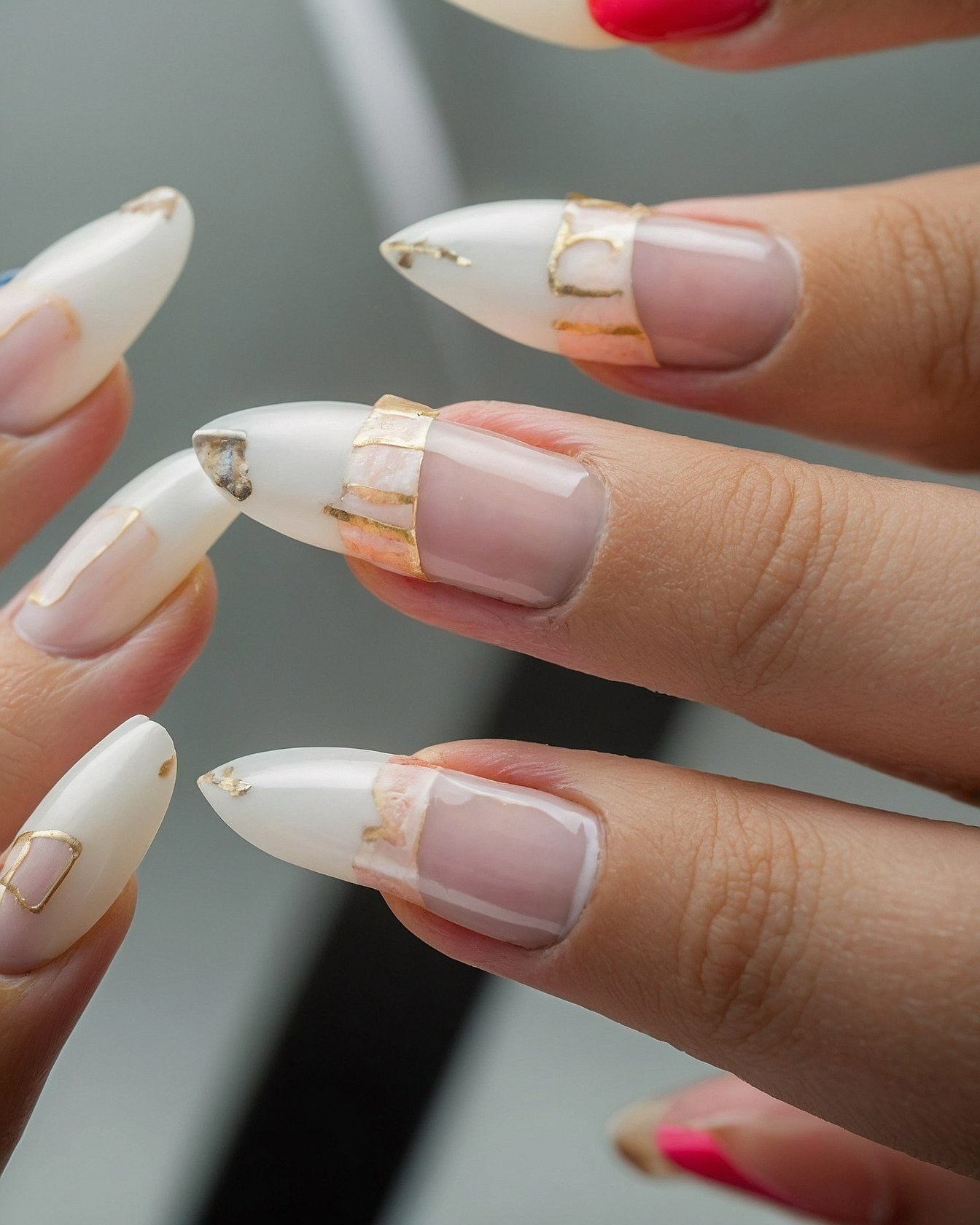 Detailed view of white almond nails with gold accents