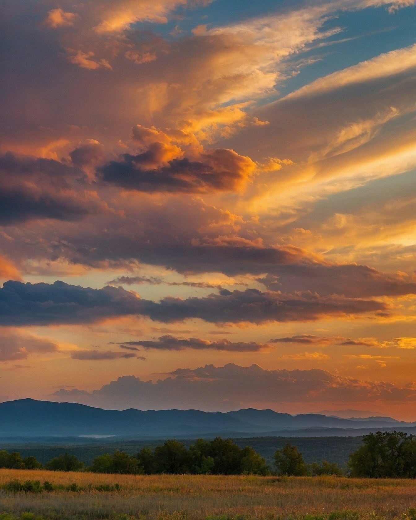 Sky lit by sunset glow over layered hills