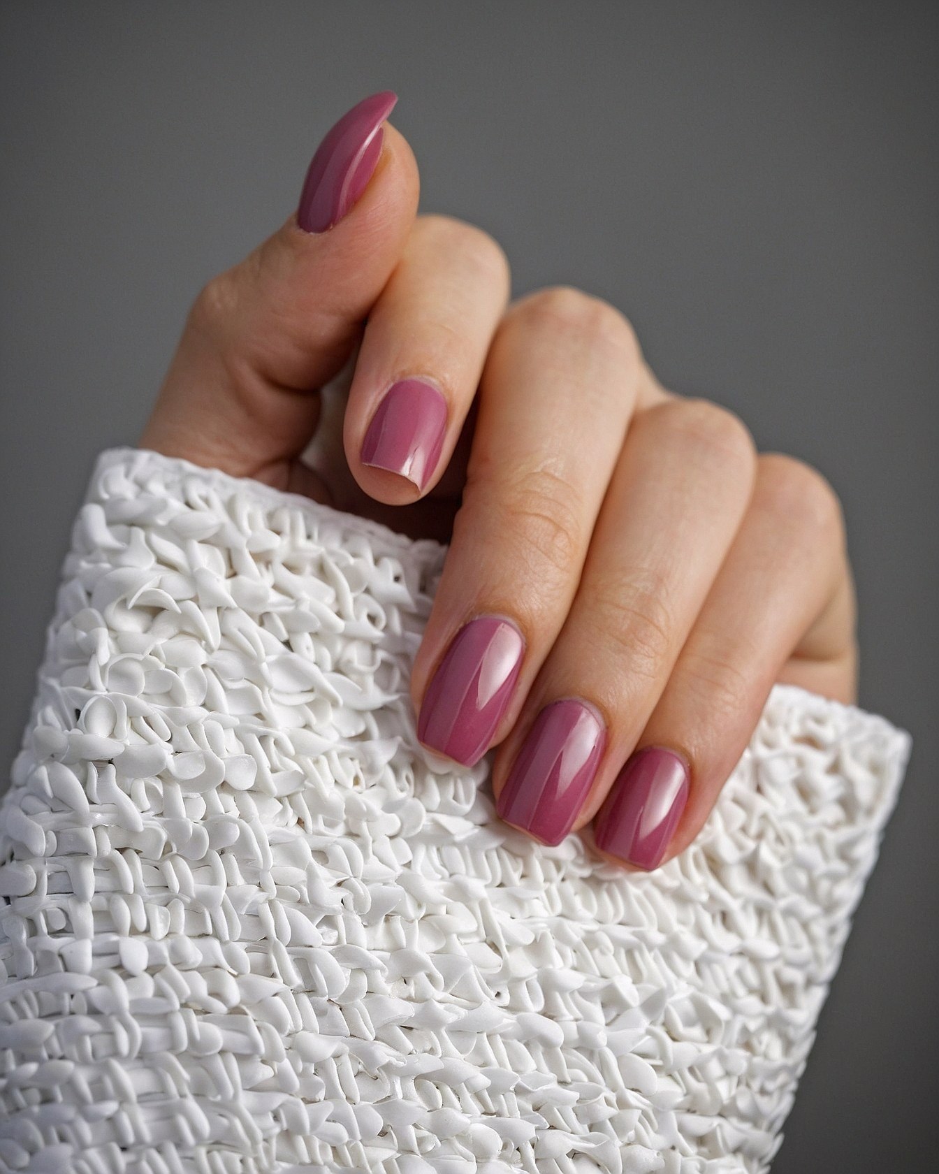 White knit cuff accenting crimson nails