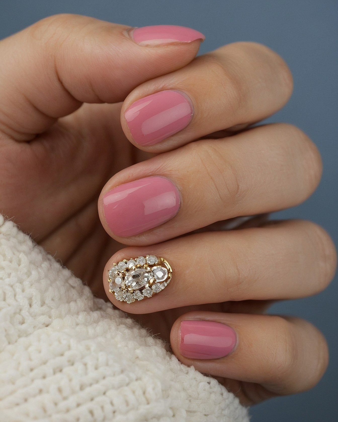 Close-up of a textured knit against pink nails