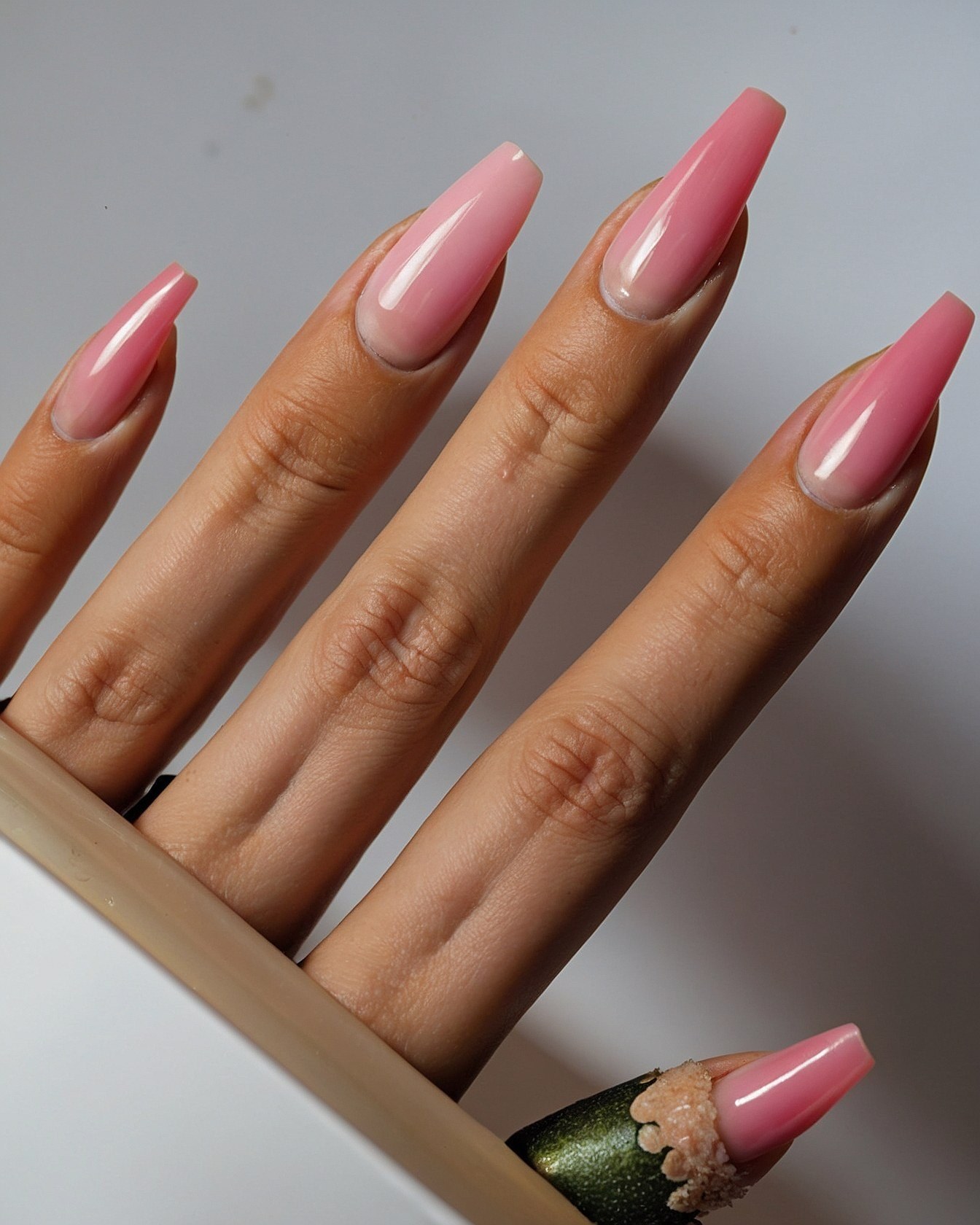 Close-up of a hand with long, glossy pink nails