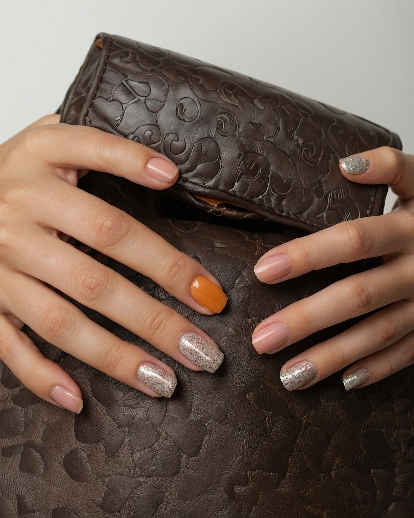 Nude and Orange Nails Against Textured Dark Brown