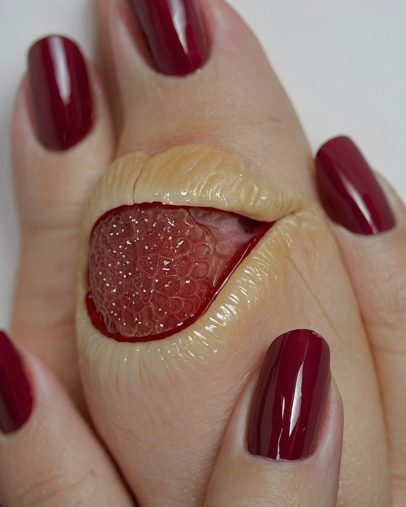 Close-up of burgundy nails and unique sculpted art