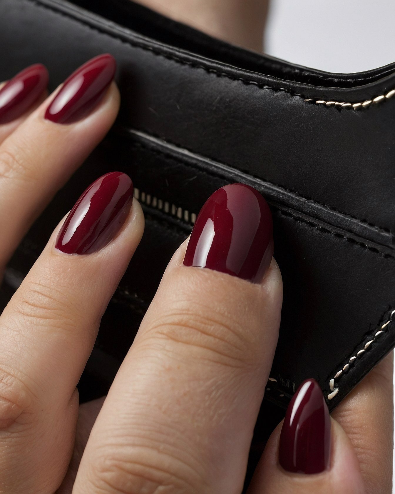 Deep Crimson Nails Against Textured Black Leather