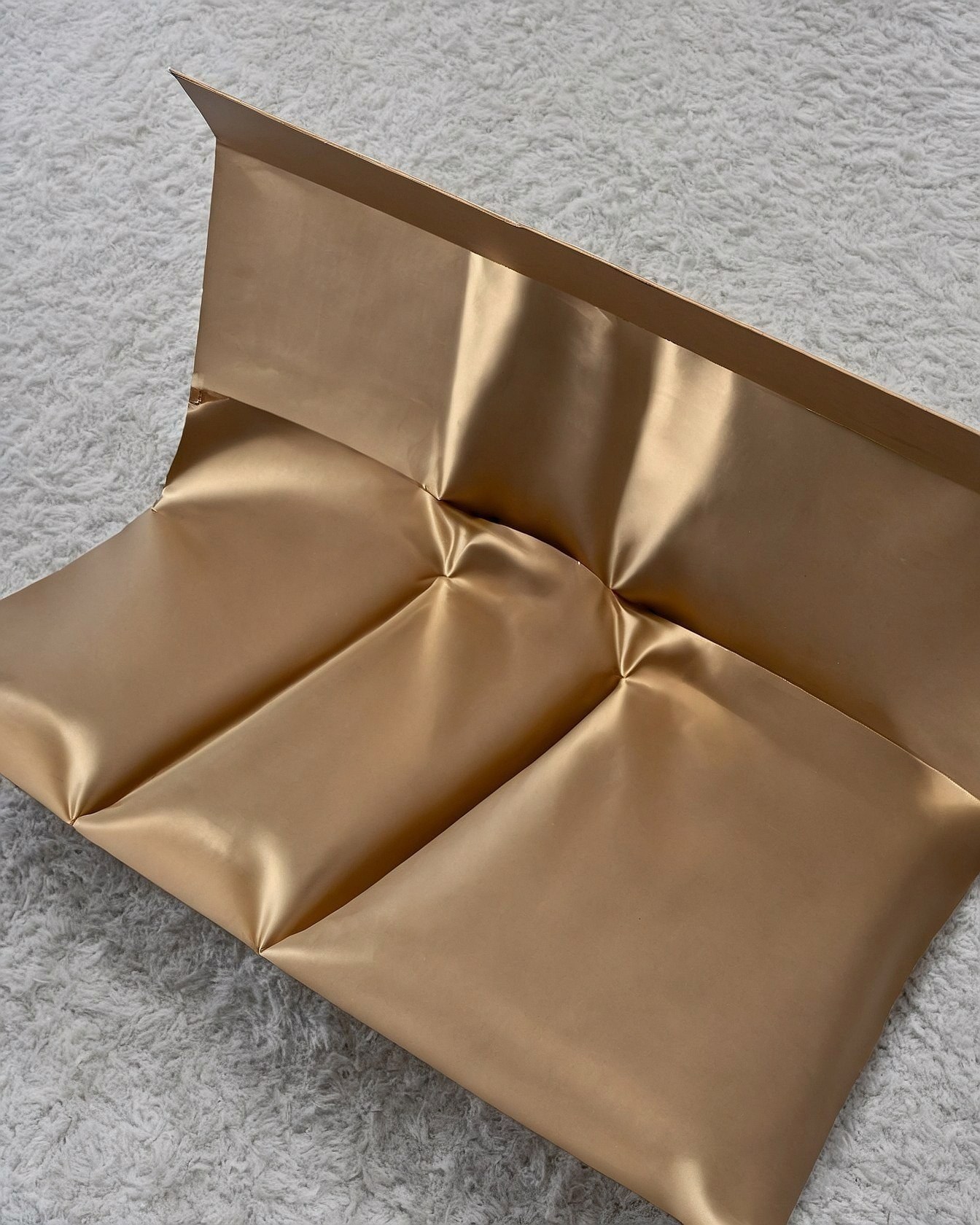 Contrasting Texture: Metallic Gold Folds on Plush White Carpet