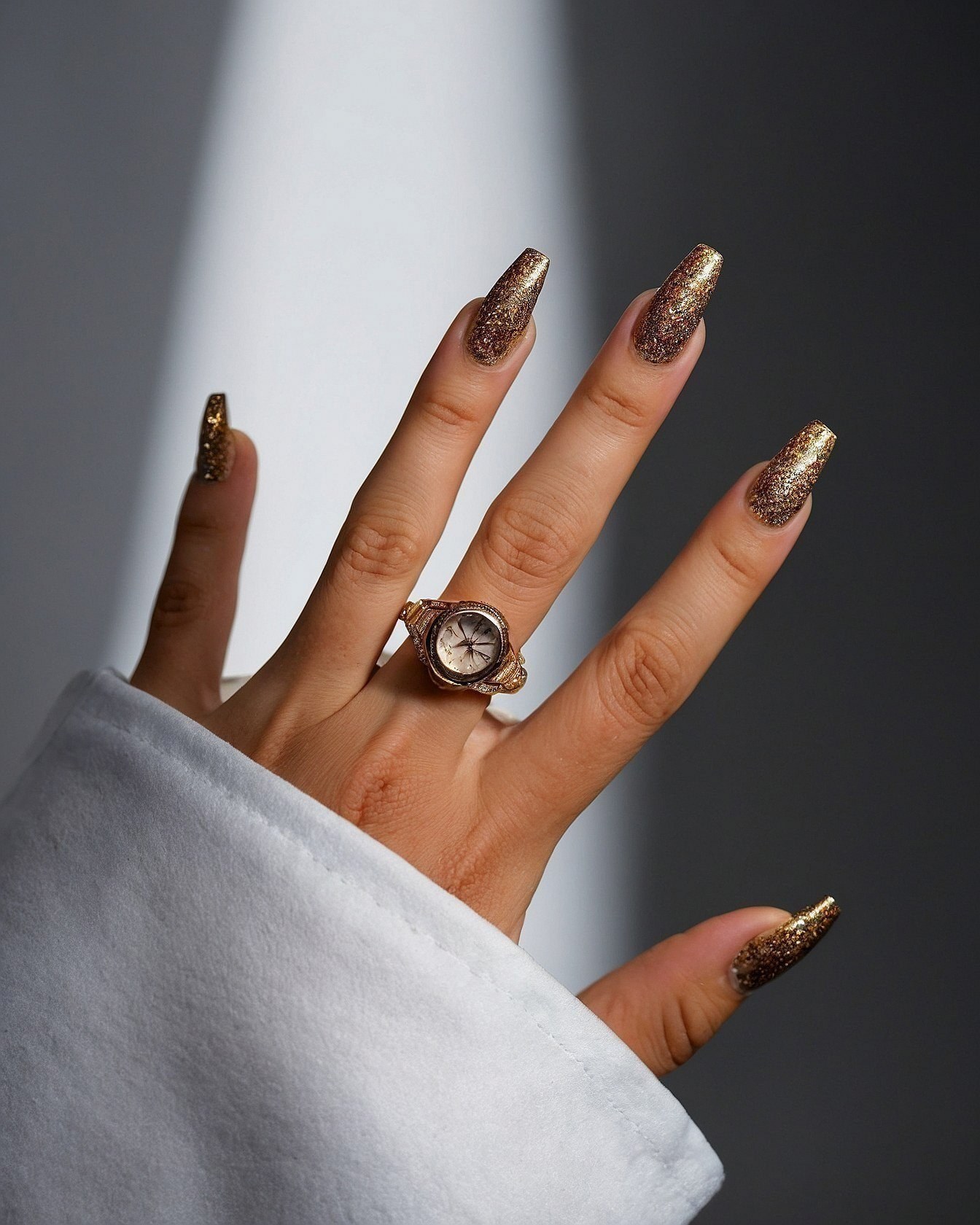 Sparkling Gold Glitter Nails Against Clean White Fabric