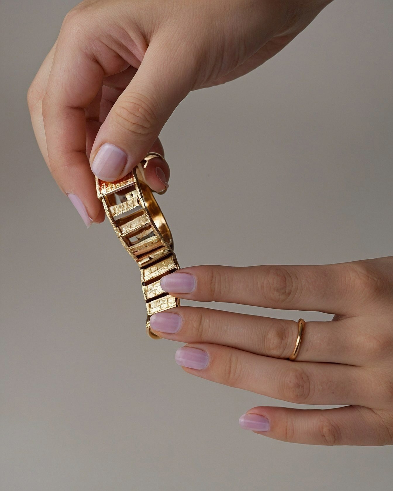 Bold gold bracelet against delicate lavender nails